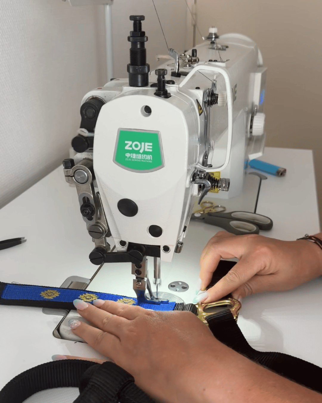photo de machine à coudre professionelle en action entrain de broder un licol noir Coyonic avec une bande bleu et des motifs couleur or métalisé
